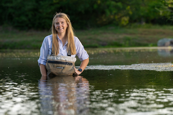 A smiling Brittany Chesser stands in a pond.