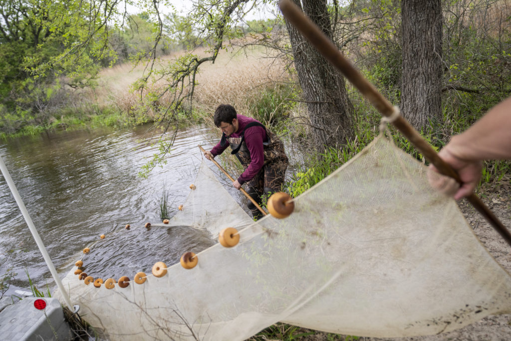 Man in the wetlands holding a fishing net with float lines