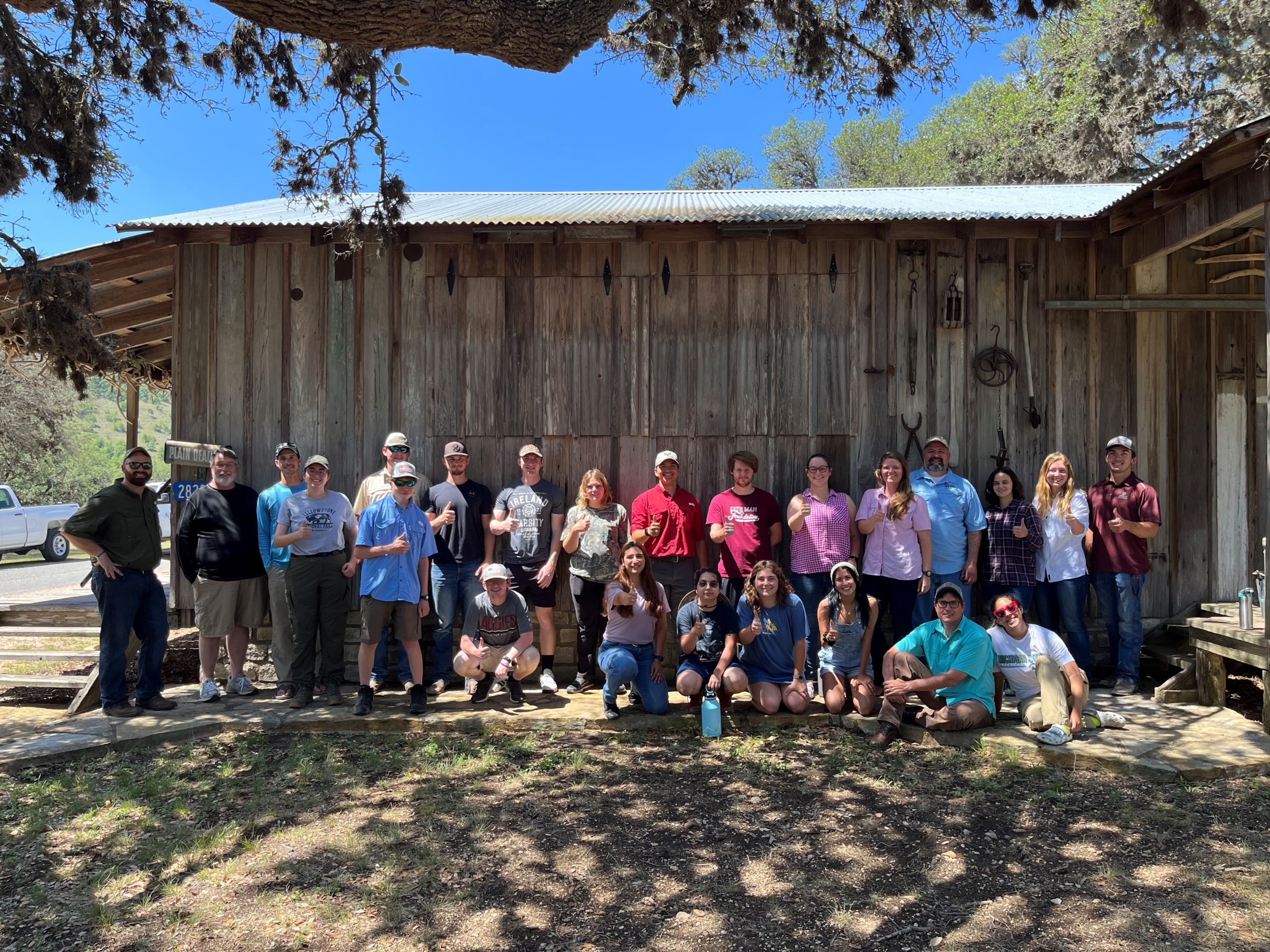 Students posing in front of a wooden building during summer camp