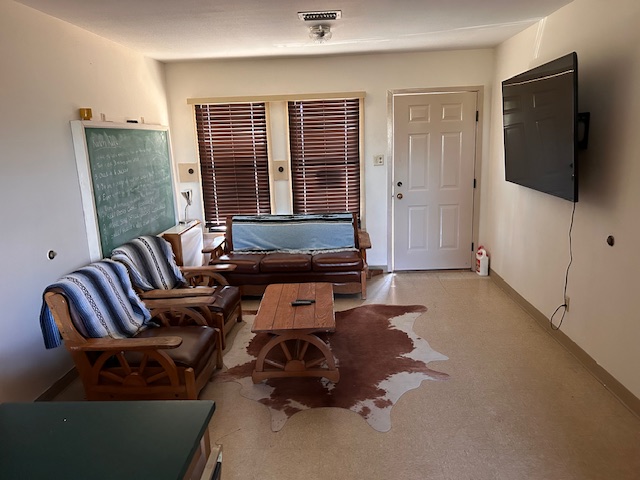 A living space with chairs, a couch, coffee table and cow skin rug.